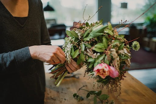 Hands tying a floral bouquet