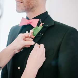 Hands pinning a boutonniere on a man in a suit