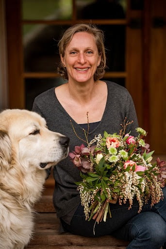 Floral designer Lexi Richards of Twiggage & Bloom holding a bouquet next to a large dog