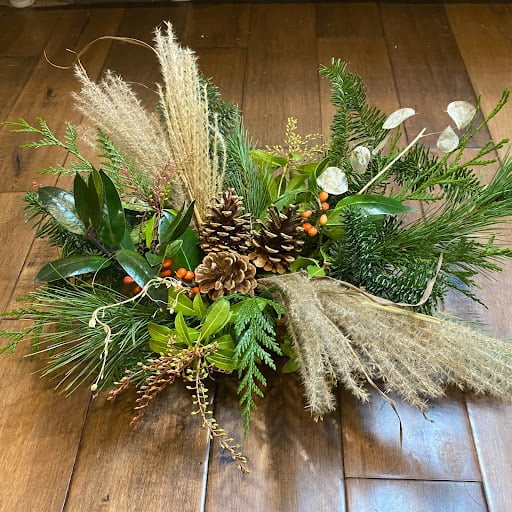 Winter flower arrangement with pinecones, greens and dried grasses.