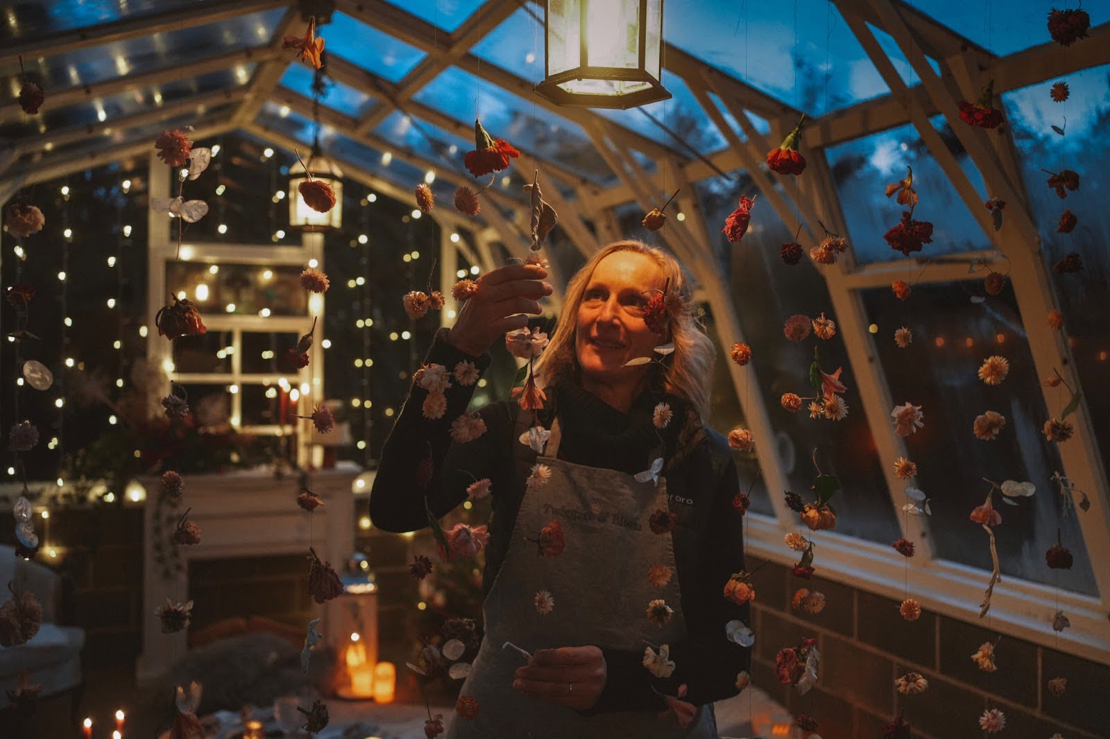 Lexi Richards, floral designer of Twiggage & Bloom adjusts a hanging curtain of flowers.