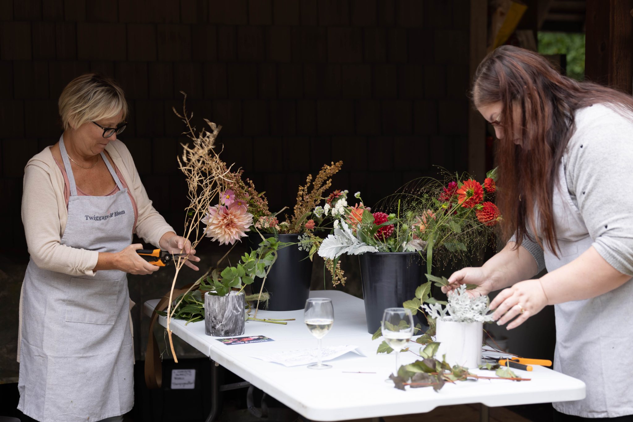Workshop participants work with flowers at a table.