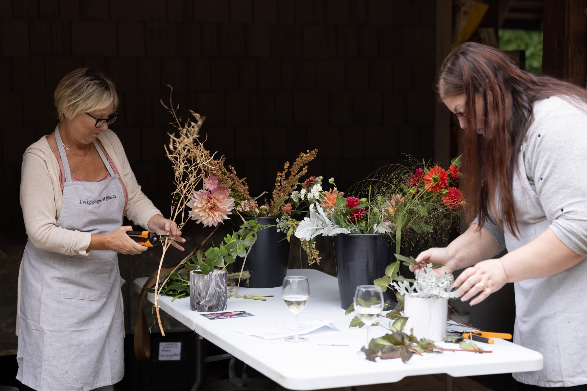 Twiggage & Bloom Workshop 2 Workshop participants work with flowers at a table.