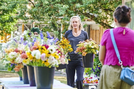 Floral designer and artist-in-residence Alexandra Richards holds two buckets full of flowers while presenting to workshop participants.