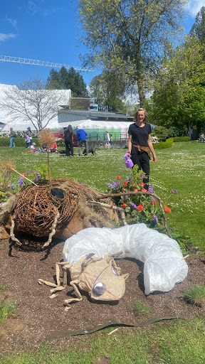 Floral Designer, Alexandra Richards, stands near her eco-sculpture of a European Chafer Beetle.